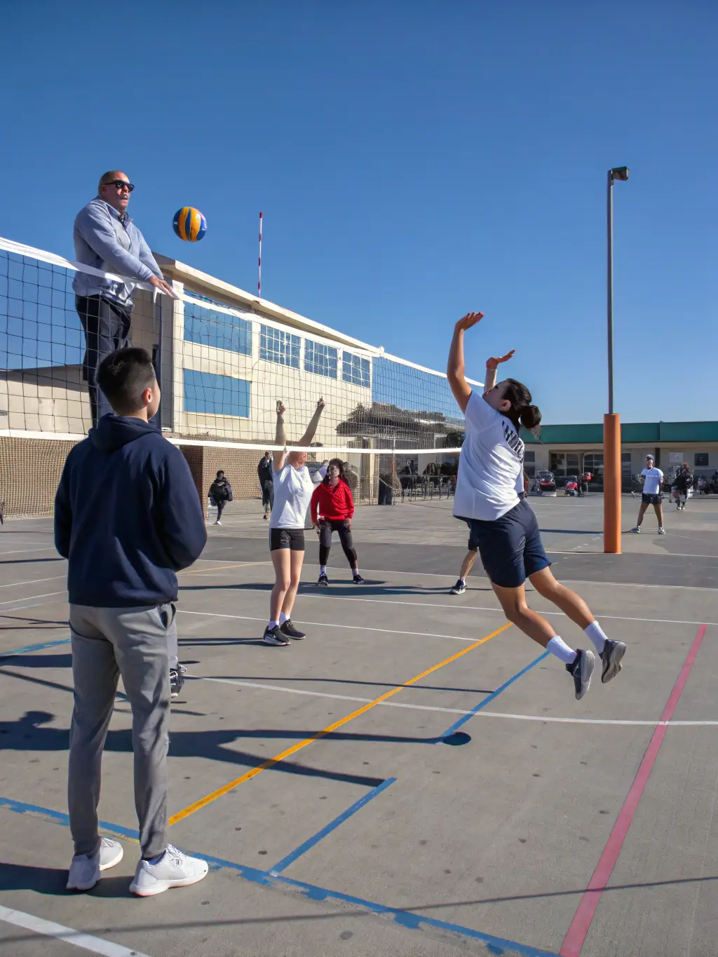 A group of students engaged in a UNSS-organized volleyball match, emphasizing coordination and communication.